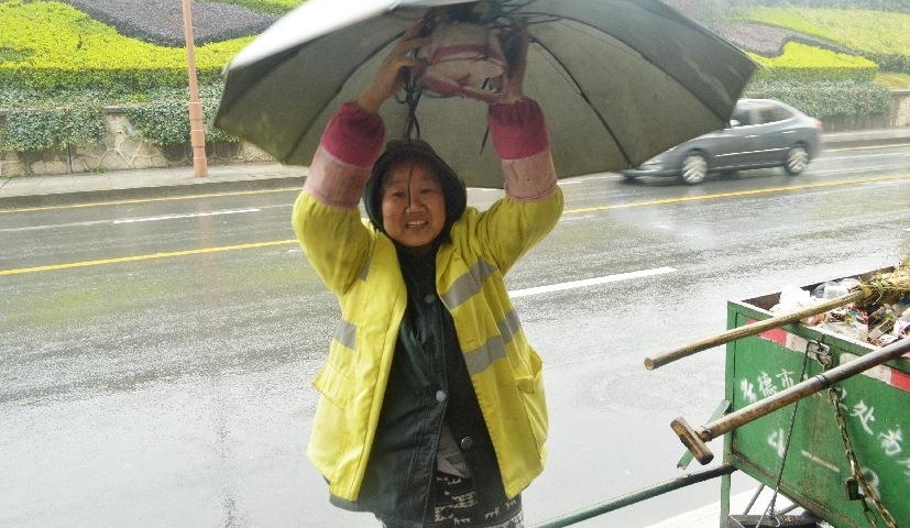 阴雨连绵,环卫工人大妈用旧雨伞和铁线圈自制“避雨神器”